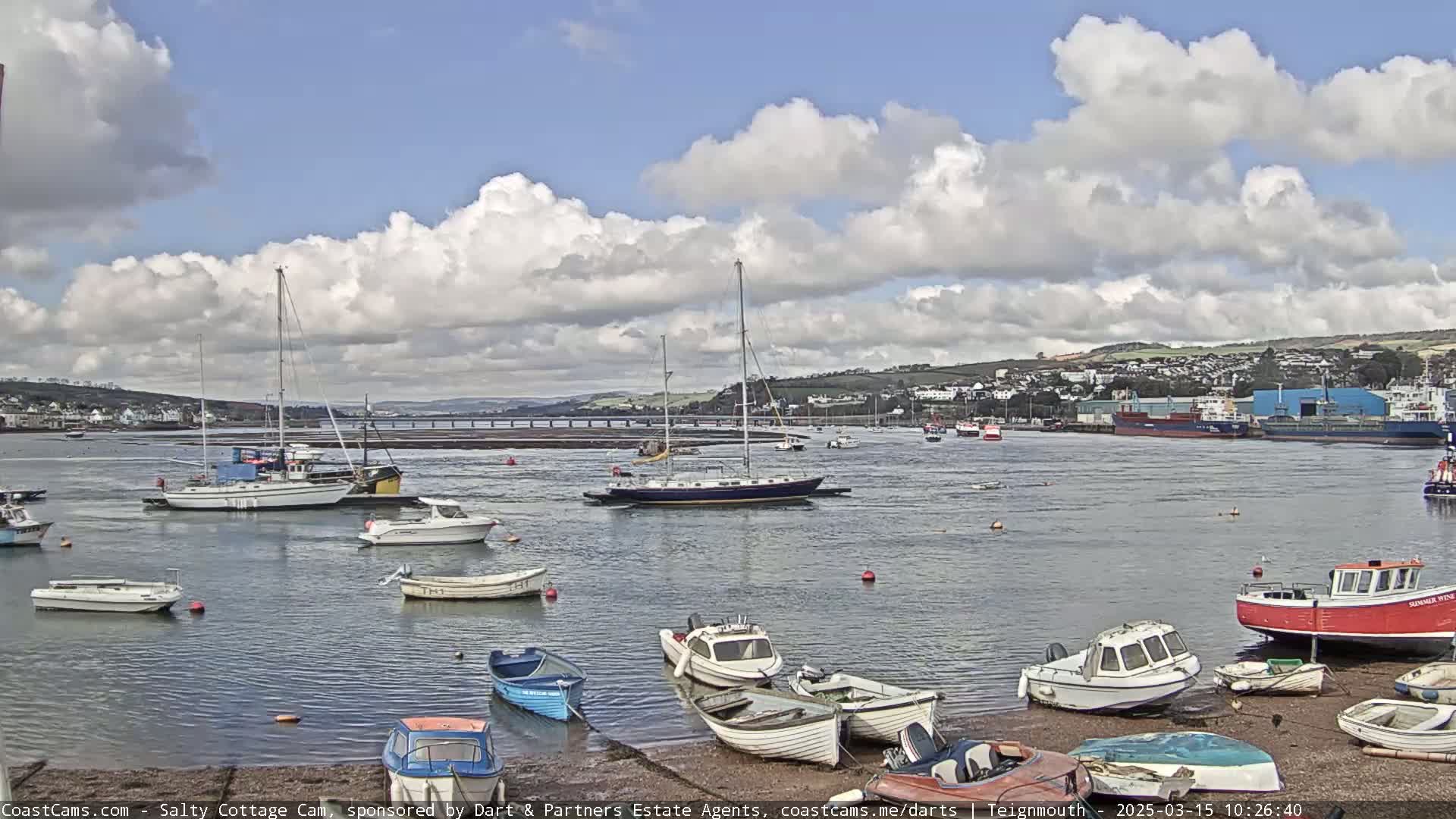Numerous boats are moored in a calm harbor under a partly cloudy sky.