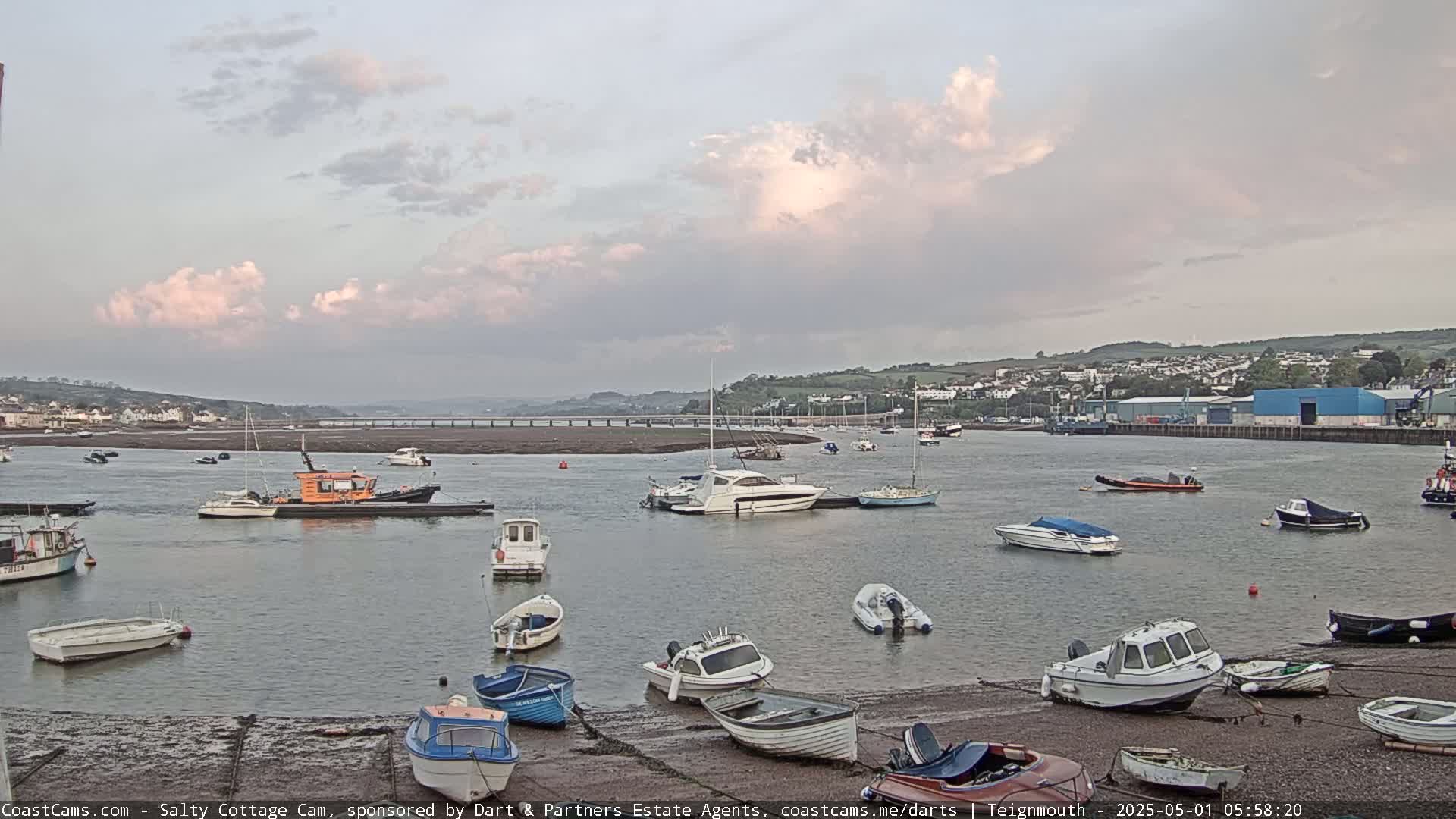 Numerous boats are moored in a calm harbor under a partly cloudy sky.