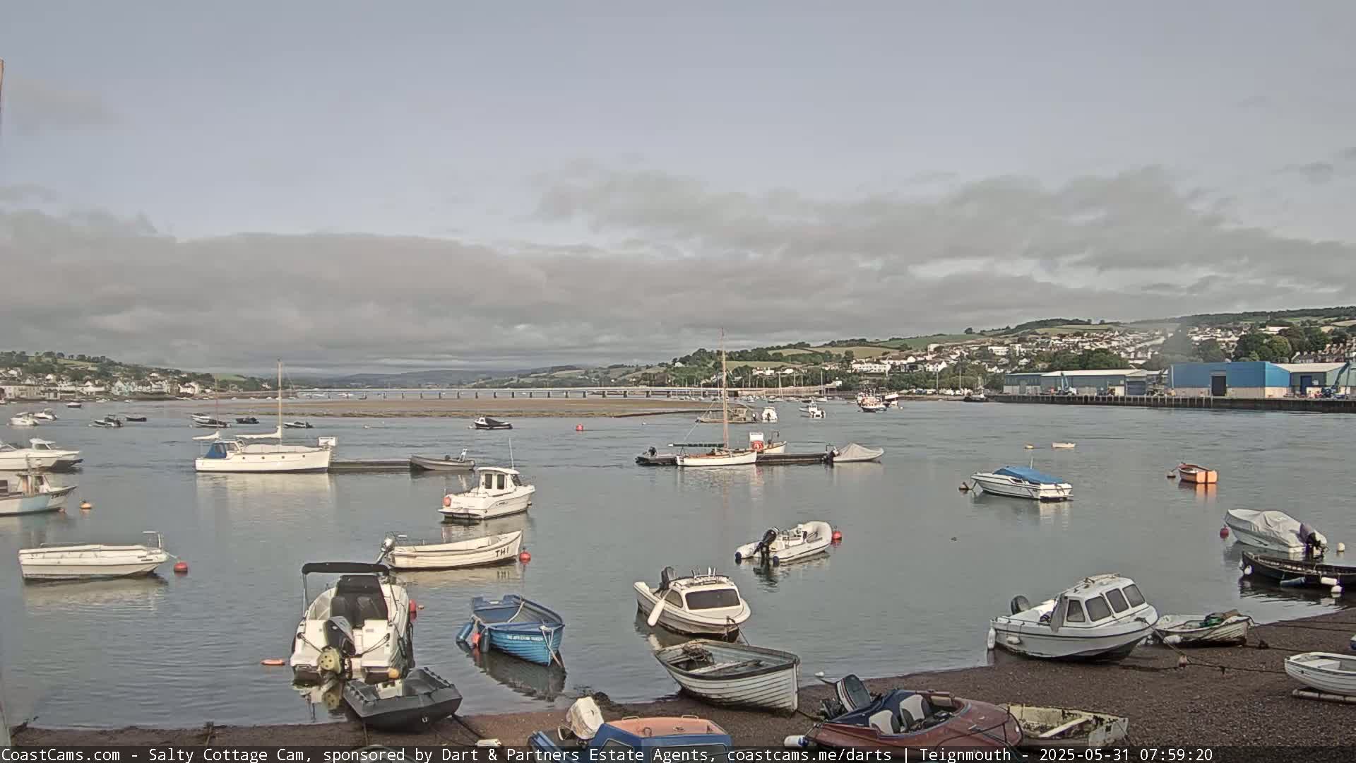 A harbor filled with numerous small motorboats and sailboats under a mostly cloudy sky.