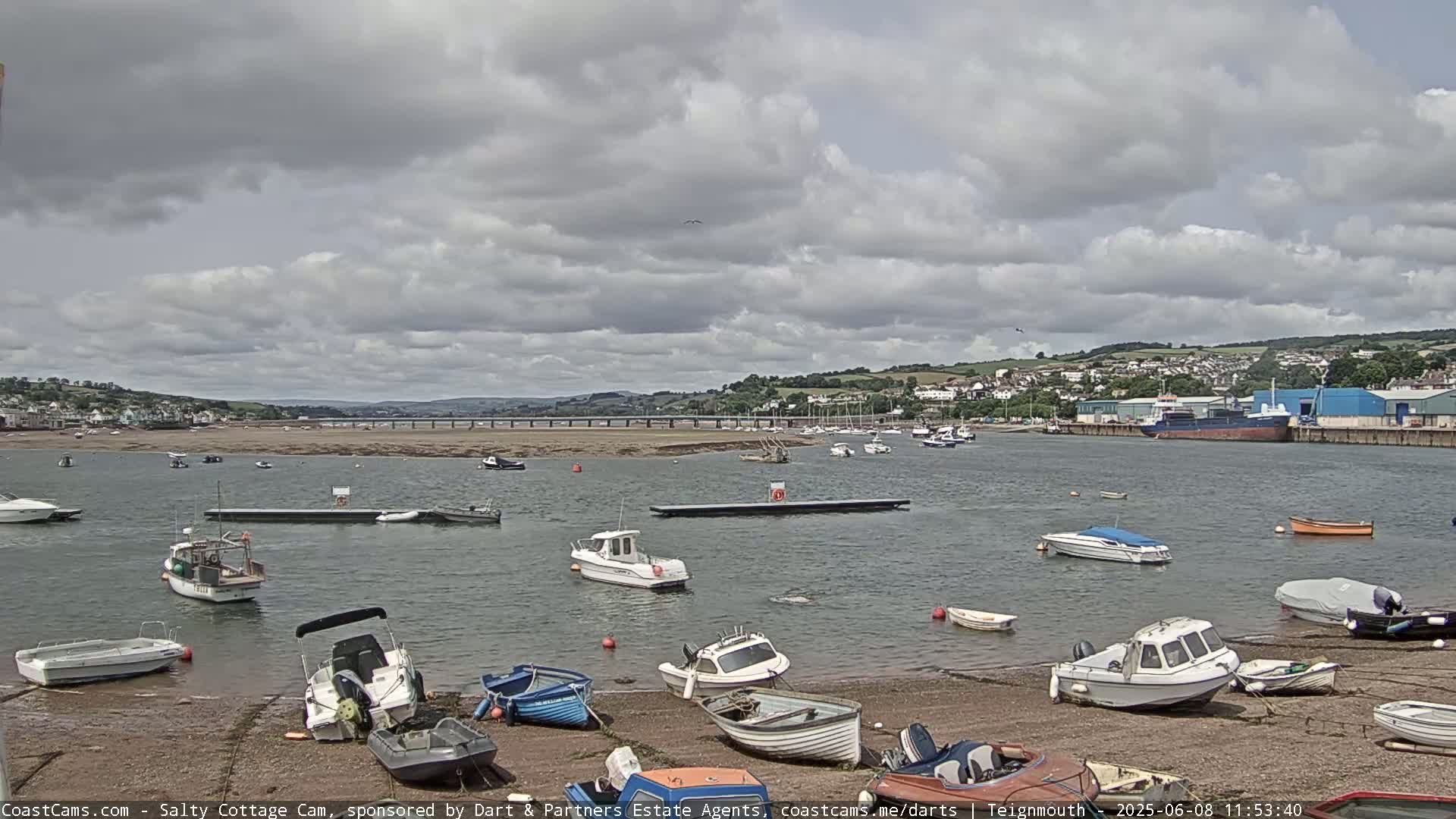 A harbor filled with numerous small boats under a partly cloudy sky.