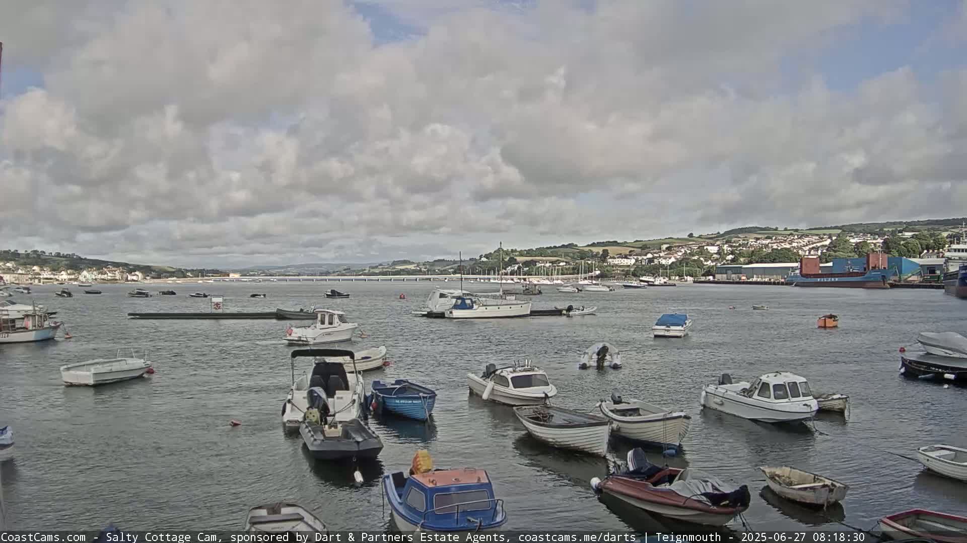 A harbor filled with numerous small motorboats under a partly cloudy sky.