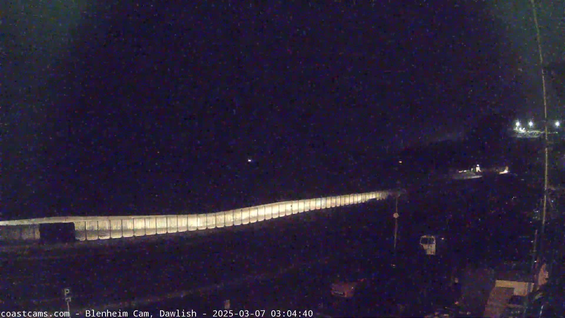 A long, illuminated barrier stretches across a dark, nighttime scene.