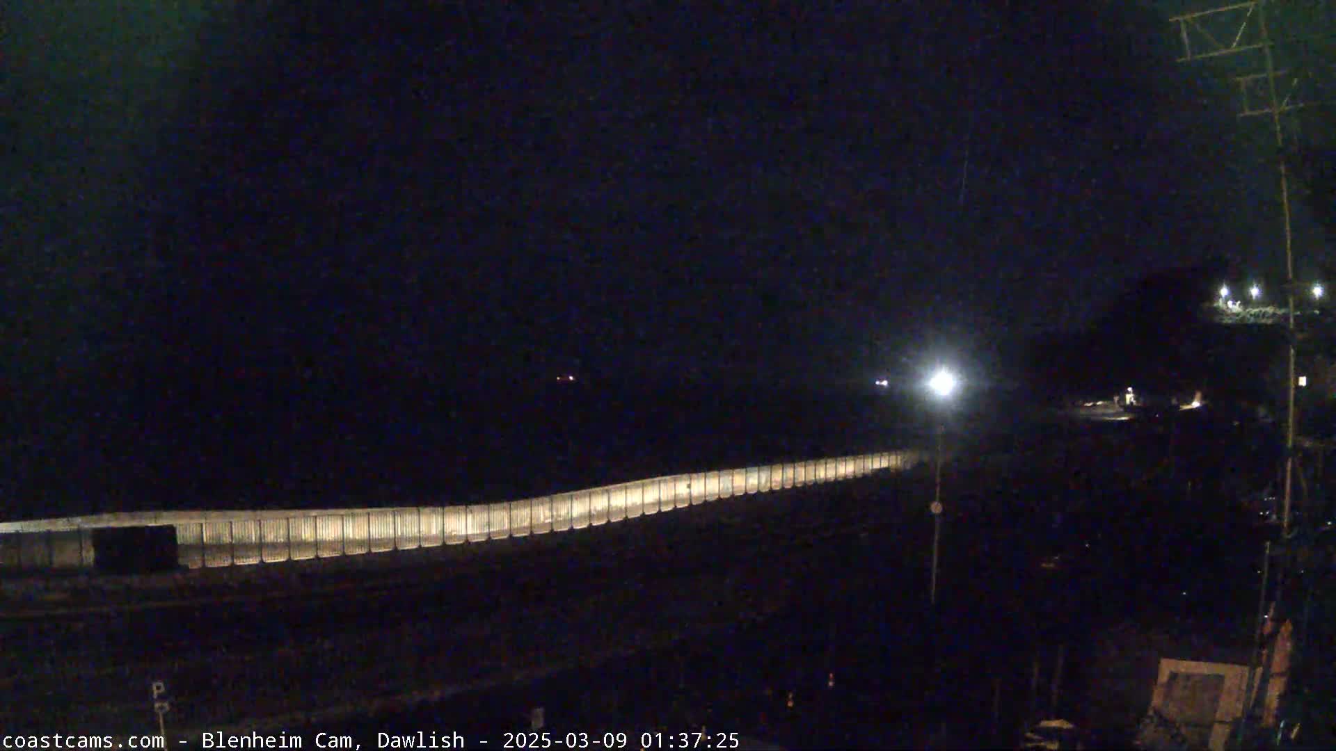 A long, illuminated barrier stretches across a dark, nighttime scene.