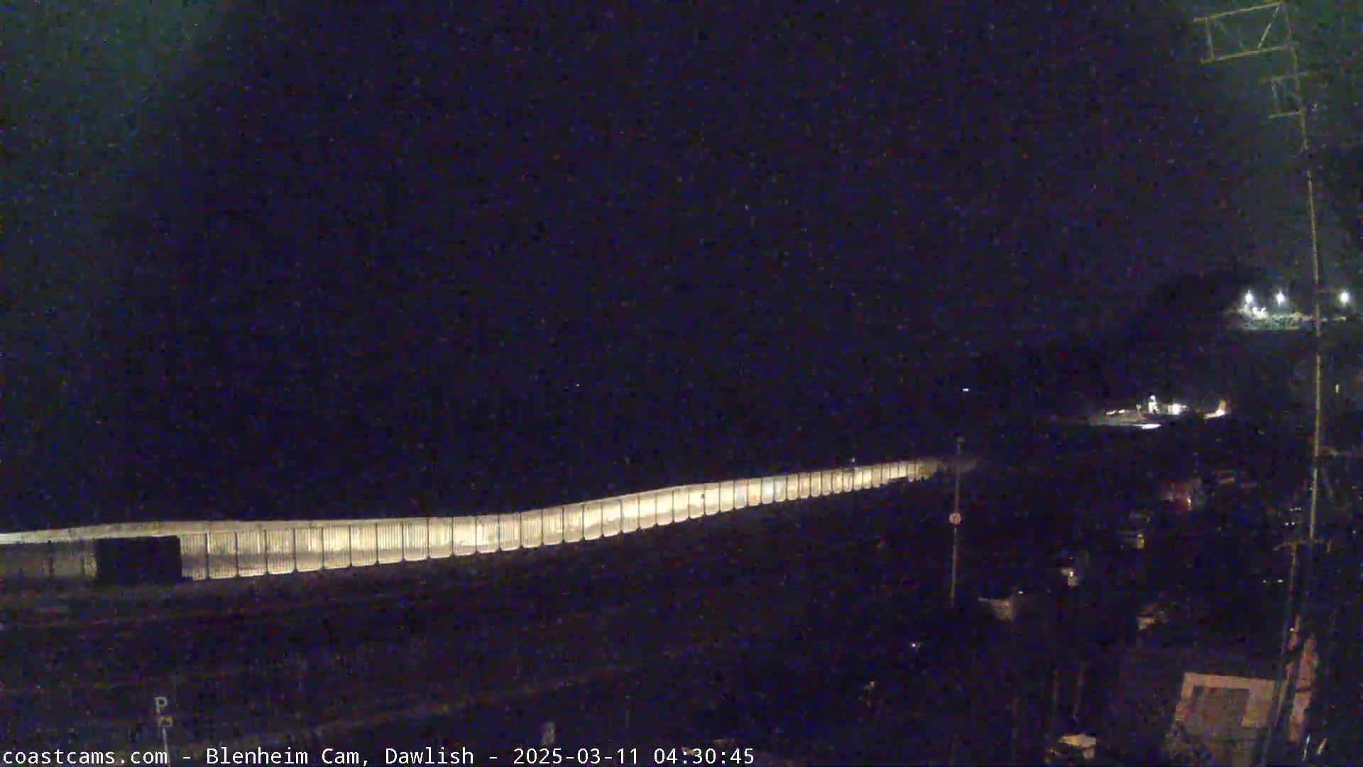 A long, illuminated barrier stretches across a dark, nighttime scene.