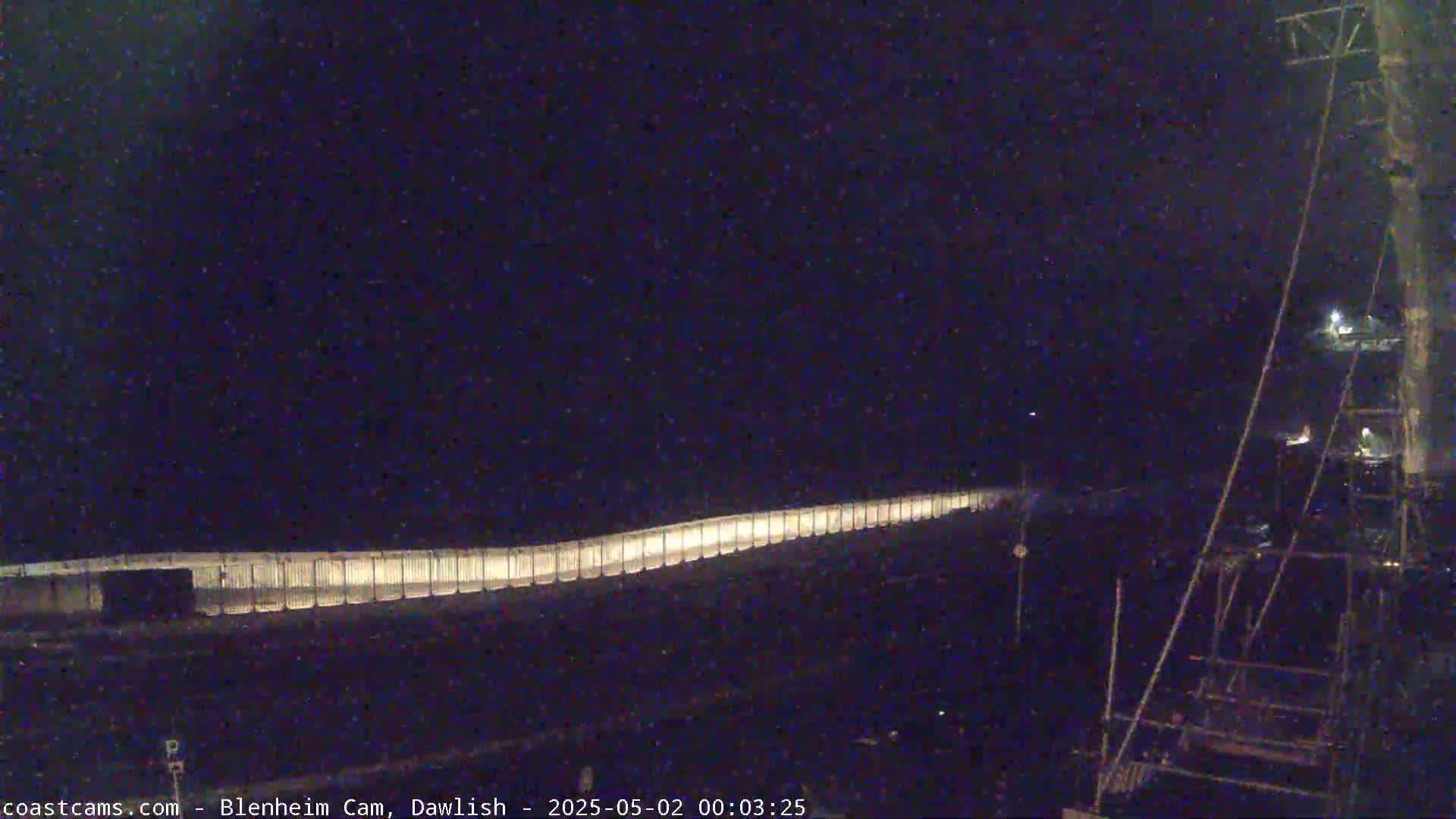 A long, illuminated barrier stretches across a dark, nighttime scene.