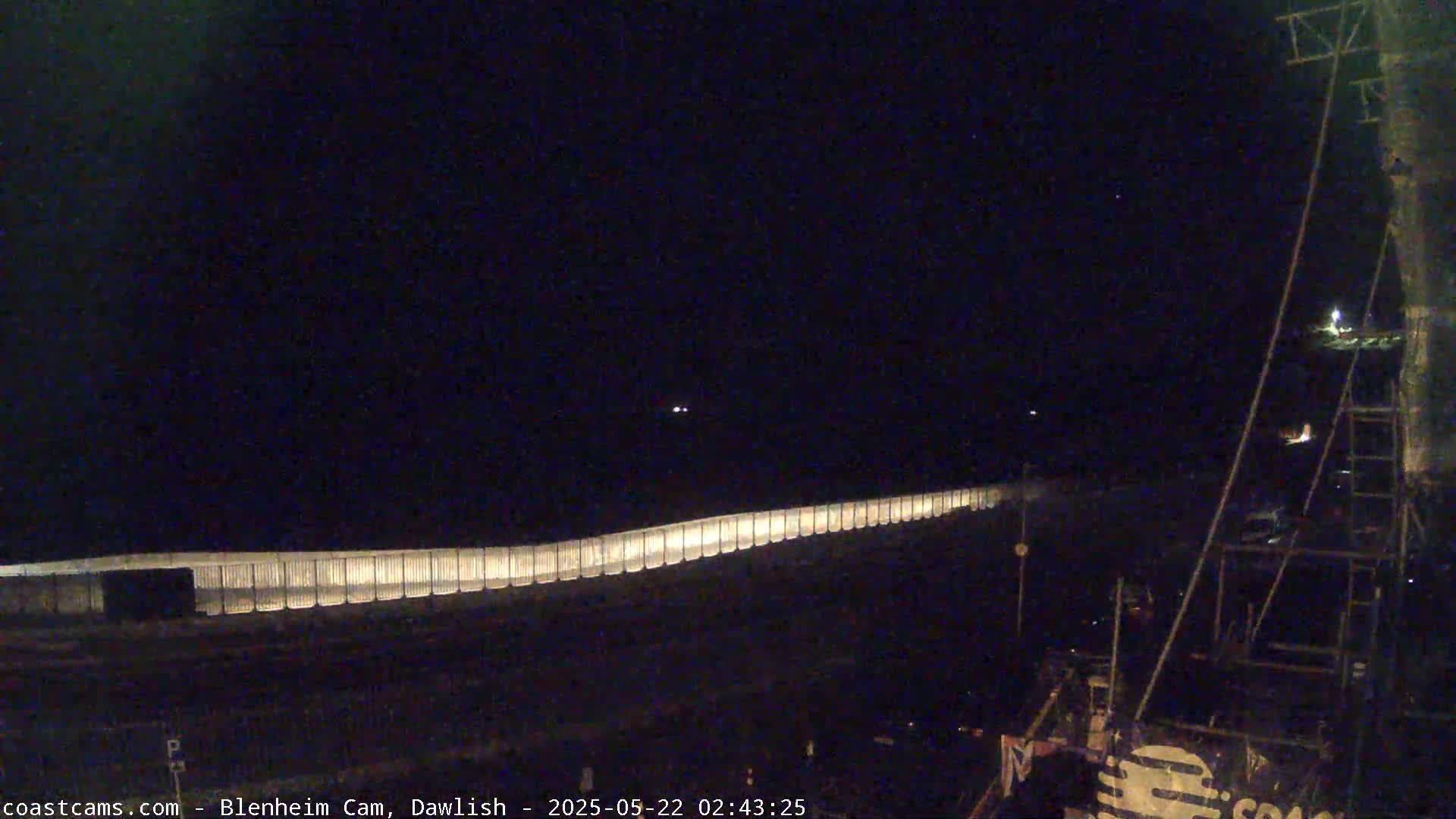 A long, illuminated fence stretches across a dark, nighttime scene.