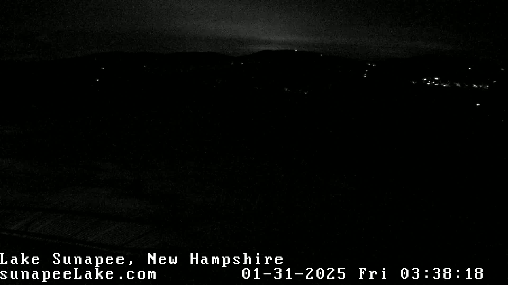 A nighttime long shot shows a dark landscape with a few distant lights under a mostly clear sky.