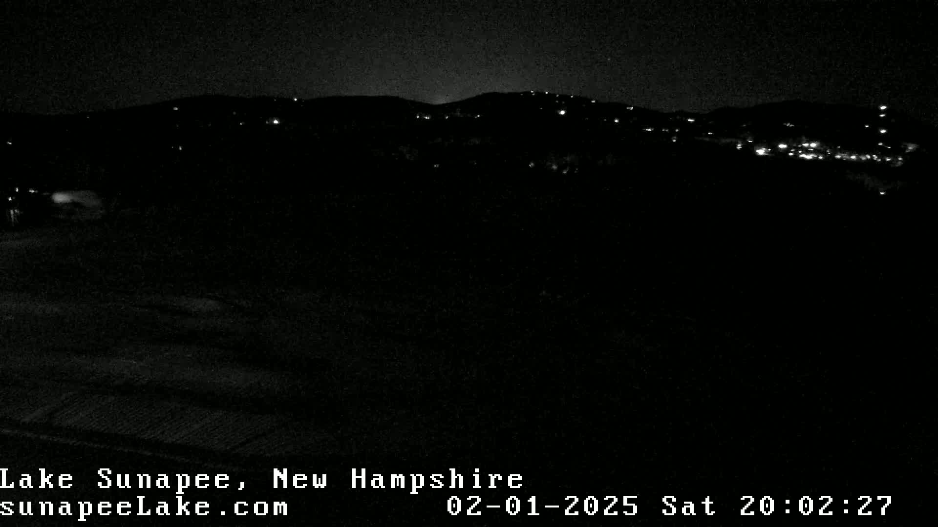 A nighttime, dark view of distant, sparsely lit hills.