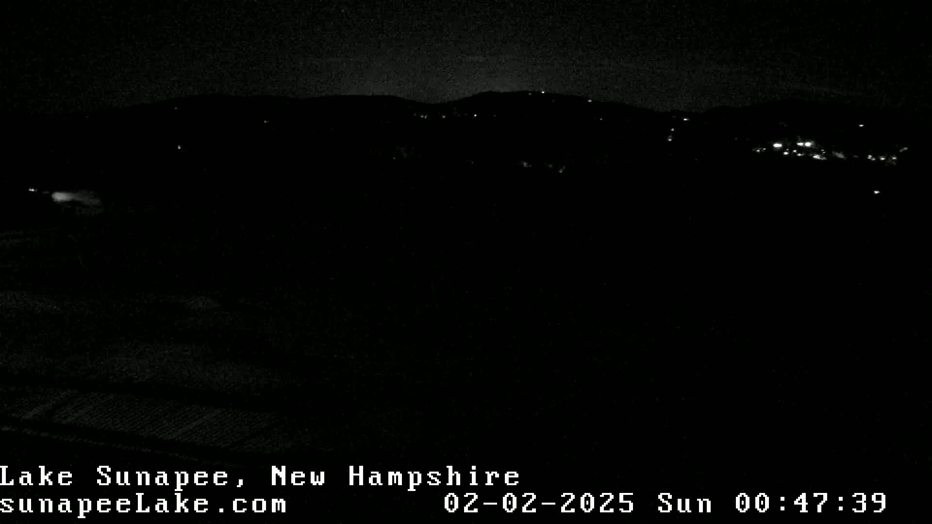 A nighttime view shows dark hills with a few distant lights under a clear, dark sky.