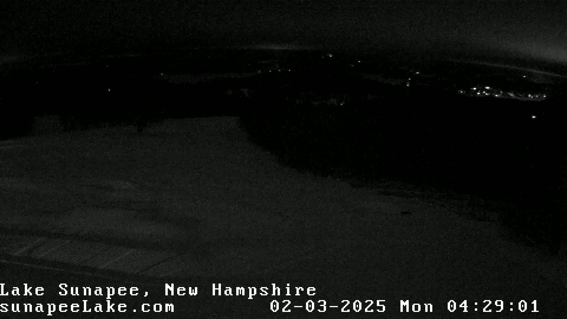 A nighttime, low-light view shows a dark landscape with a few distant lights.