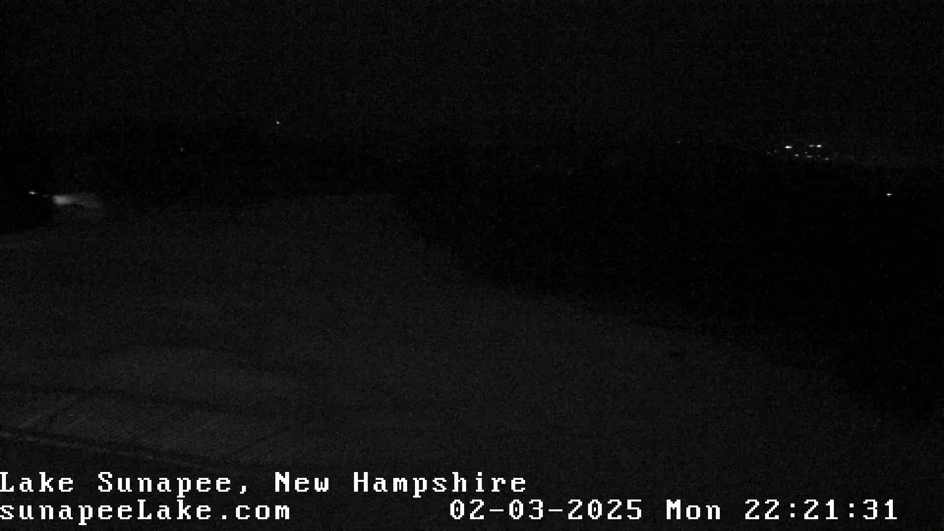 A dark, nighttime view of a landscape with a few distant lights visible.