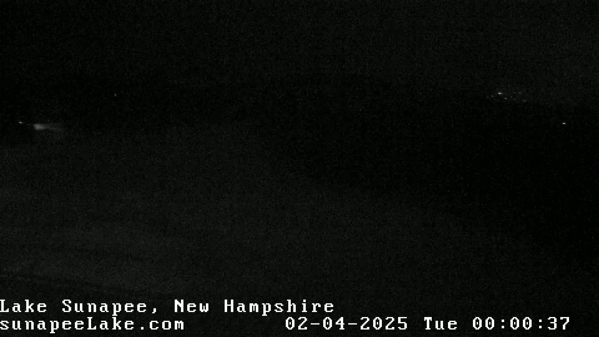 A dark, nighttime scene shows a few distant lights in the far horizon under a clear sky.
