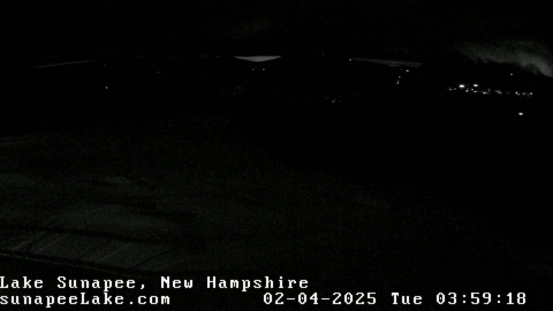 A nighttime, long-range view of dimly lit buildings and a dark landscape.