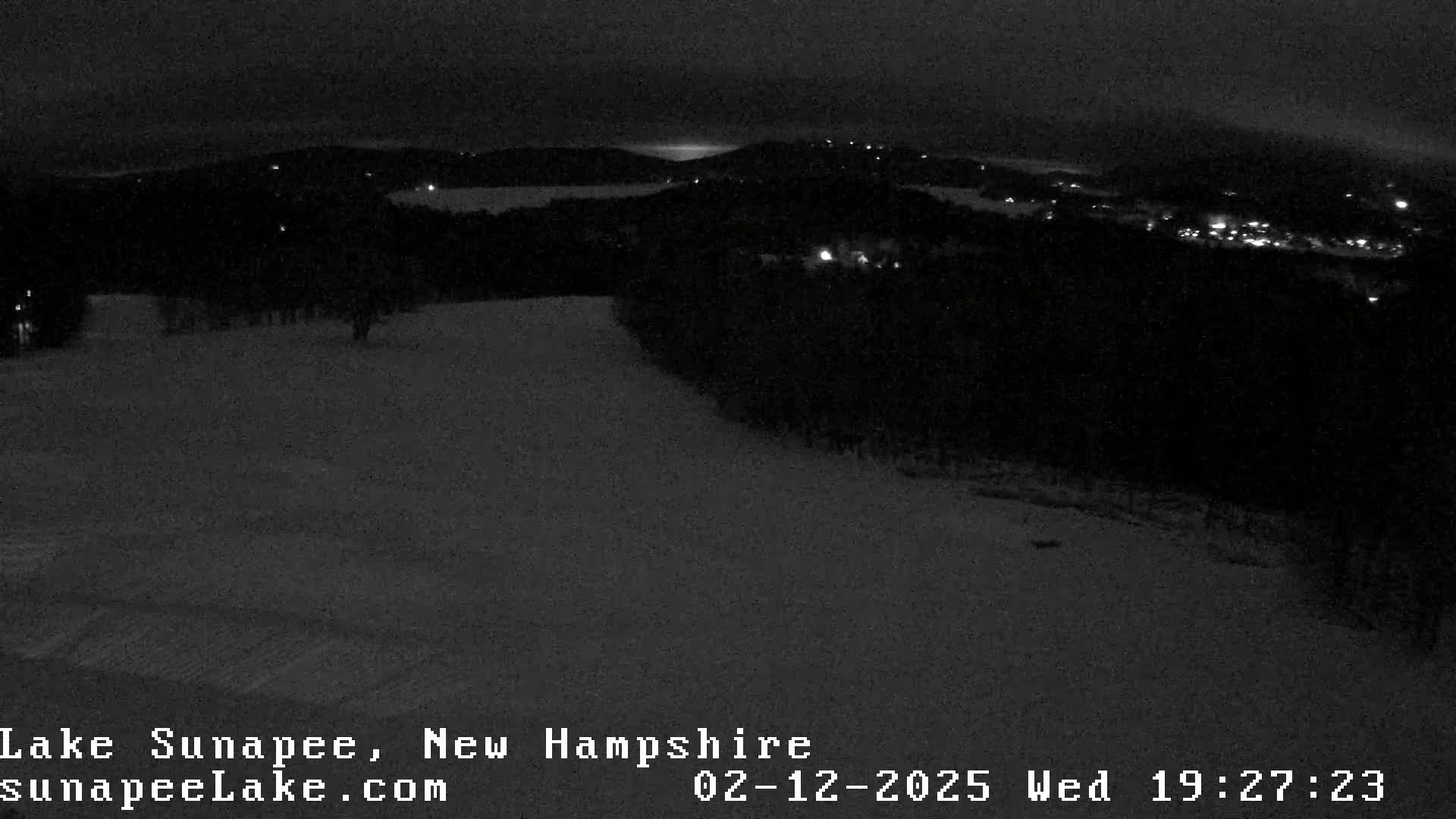 A nighttime, snow-covered landscape is visible, with a town's lights in the distance.