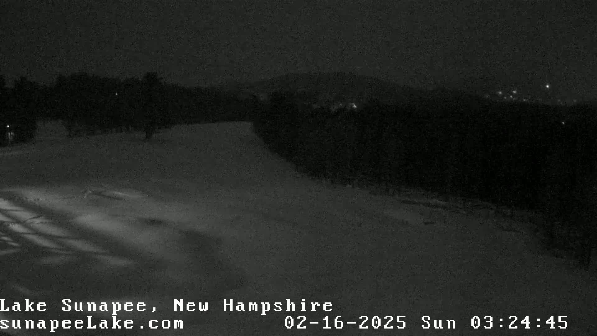 A snow-covered landscape is visible at night, illuminated by faint lights in the distance.