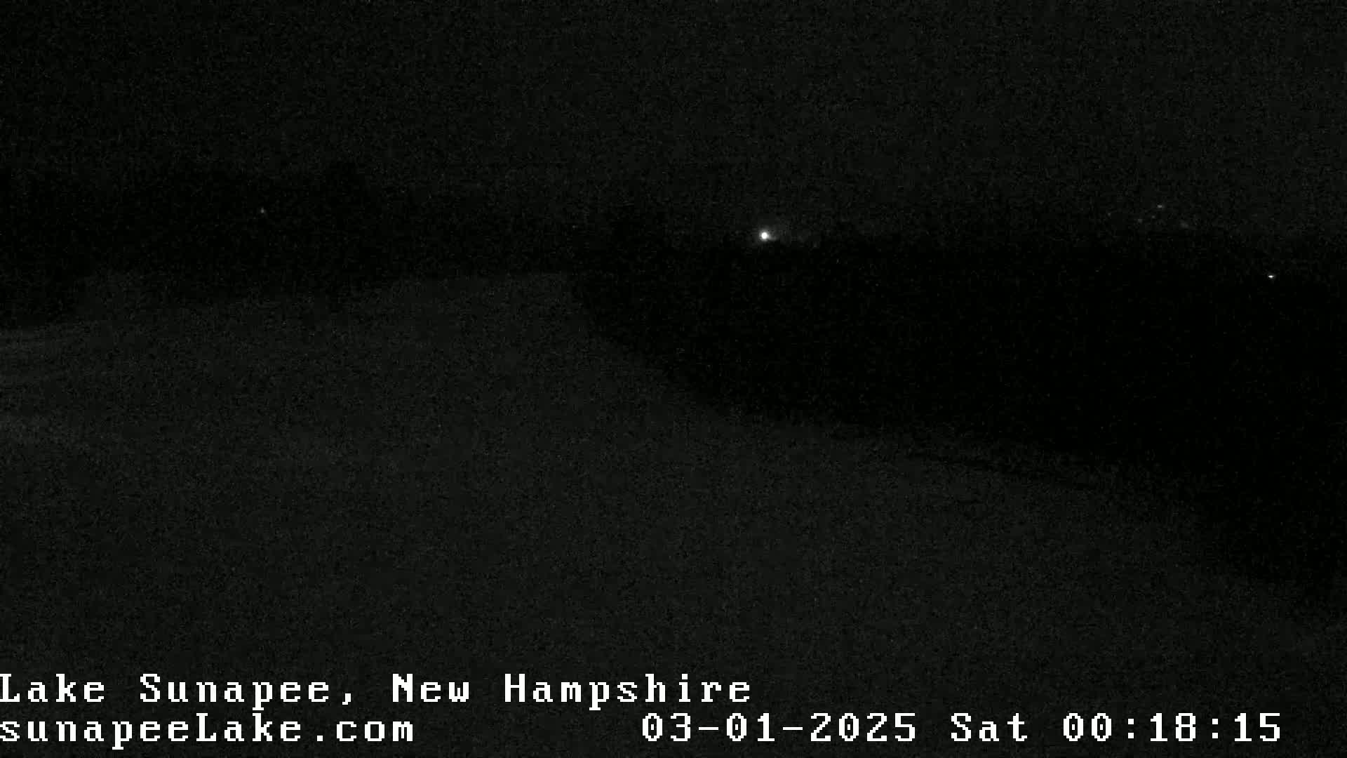 A dark, nighttime landscape is visible, with a few faint lights in the distance.