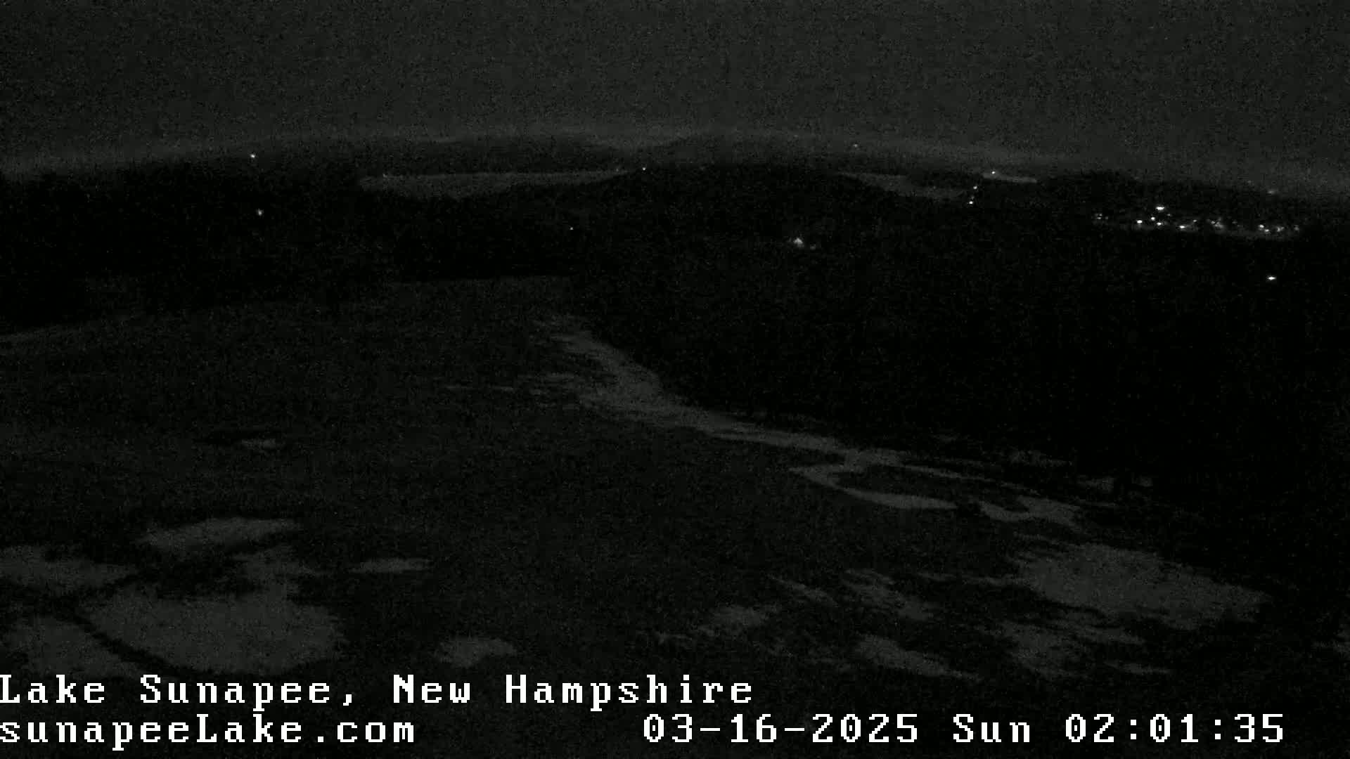 A nighttime, snow-covered landscape is visible, with distant lights suggesting a town or village in the background.