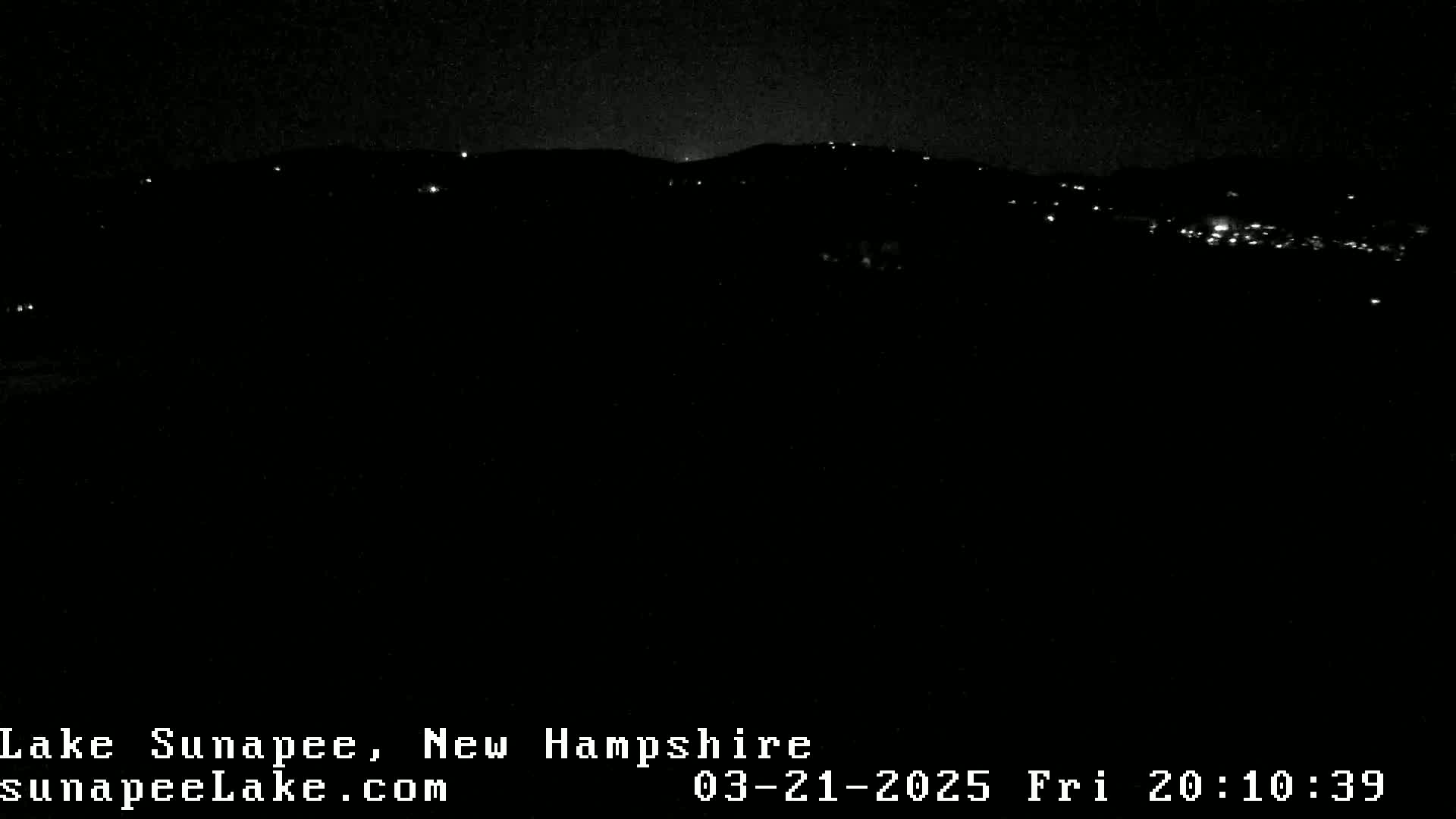 A nighttime long shot shows a dark landscape with a few scattered lights visible in the distance on a hill.