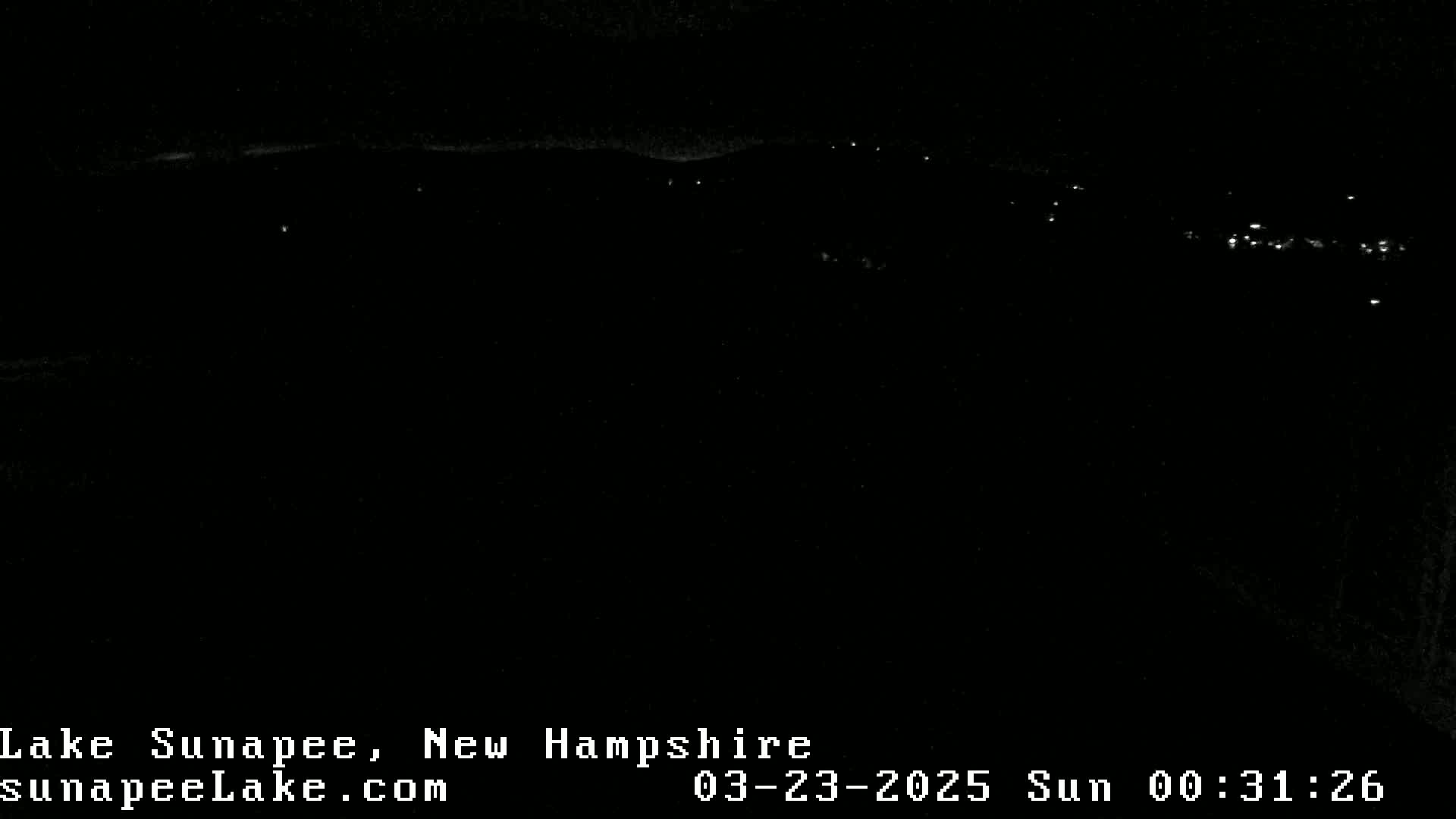 A nighttime, long-range view shows a dark landscape with a few distant lights.