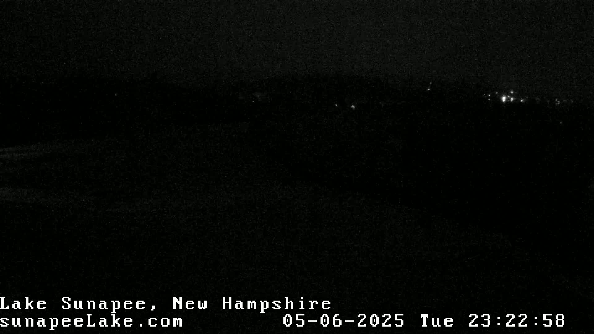 A dark, nighttime scene shows a distant line of faint lights in the far background.