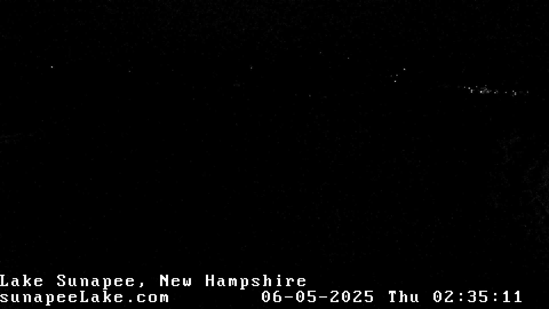 A dark nighttime scene shows a distant line of faint lights.