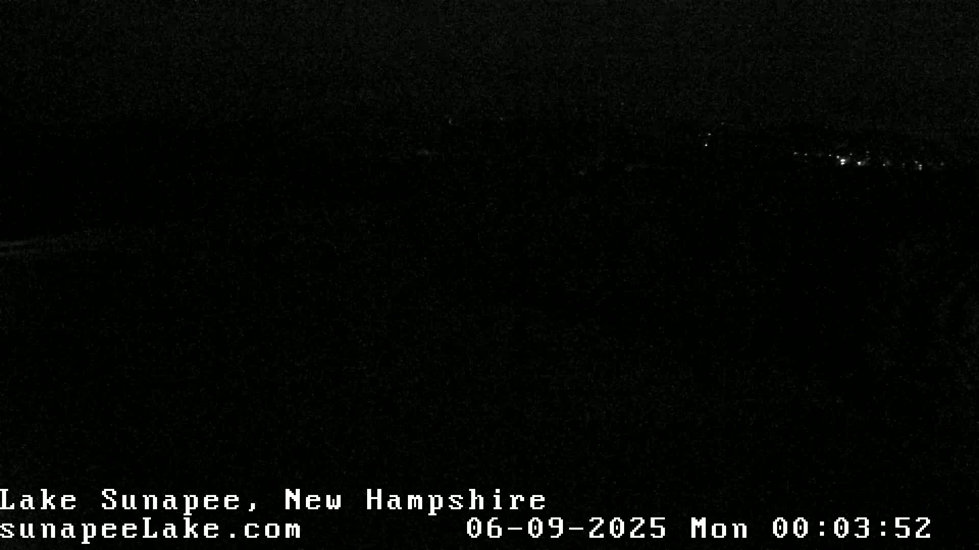 A nighttime long shot shows a distant line of faint lights on a dark horizon under a clear, dark sky.