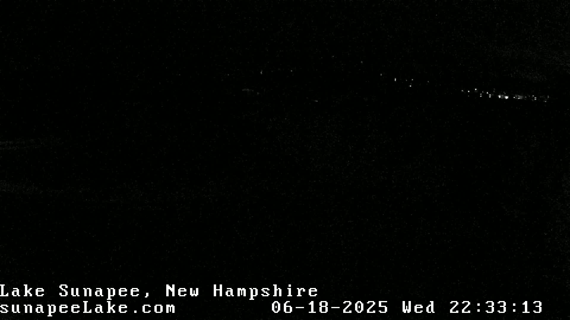 A nighttime, low-light image shows a distant line of faint lights across the bottom of the frame.
