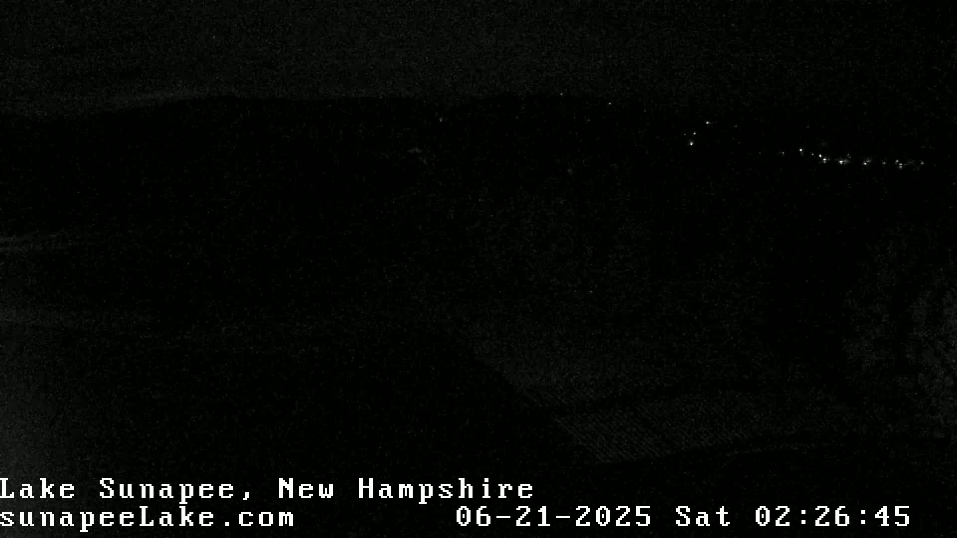 A dark, nighttime scene shows a line of distant lights across the horizon.