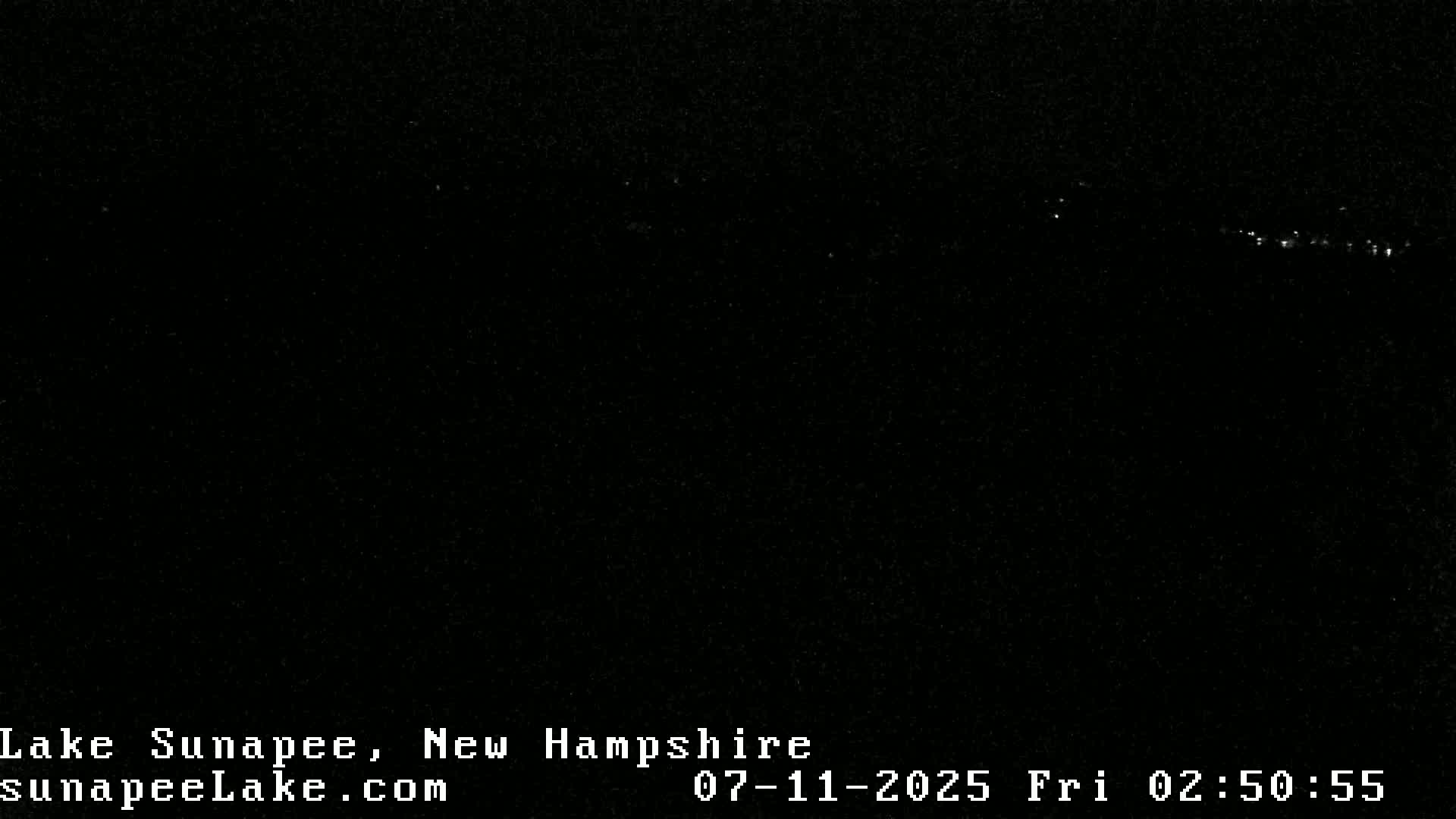 A dark, nighttime scene shows a faint line of distant lights on the horizon.