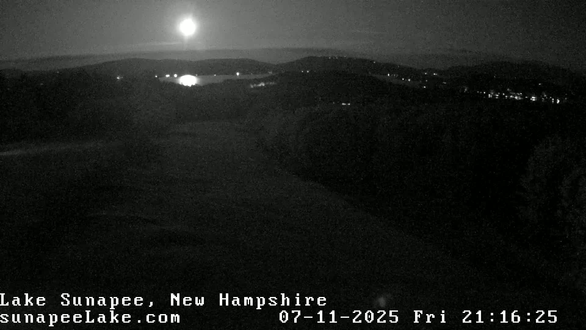 A dark, nighttime scene shows a faint line of distant lights on the horizon.