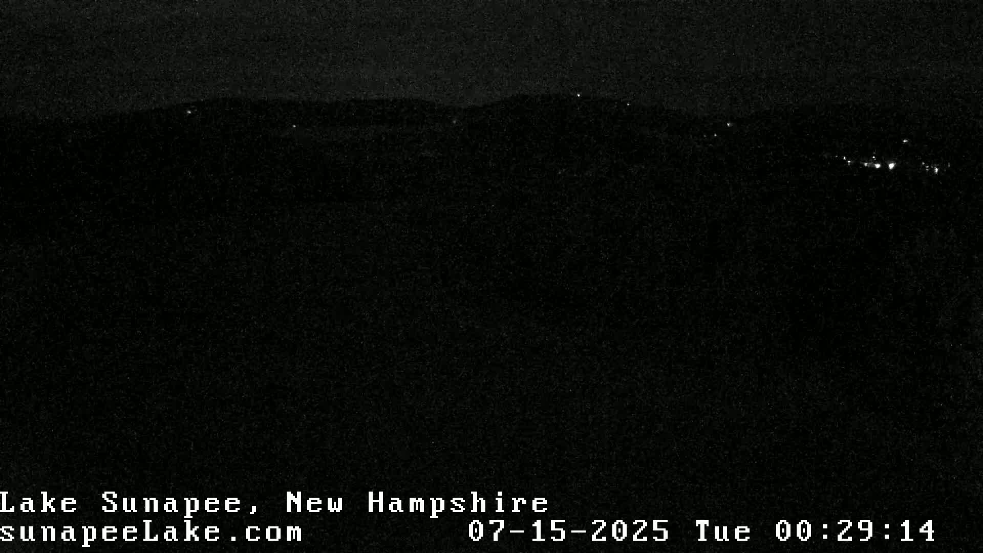 A dark, nighttime landscape is visible, showing a distant line of lights against a mostly black sky.