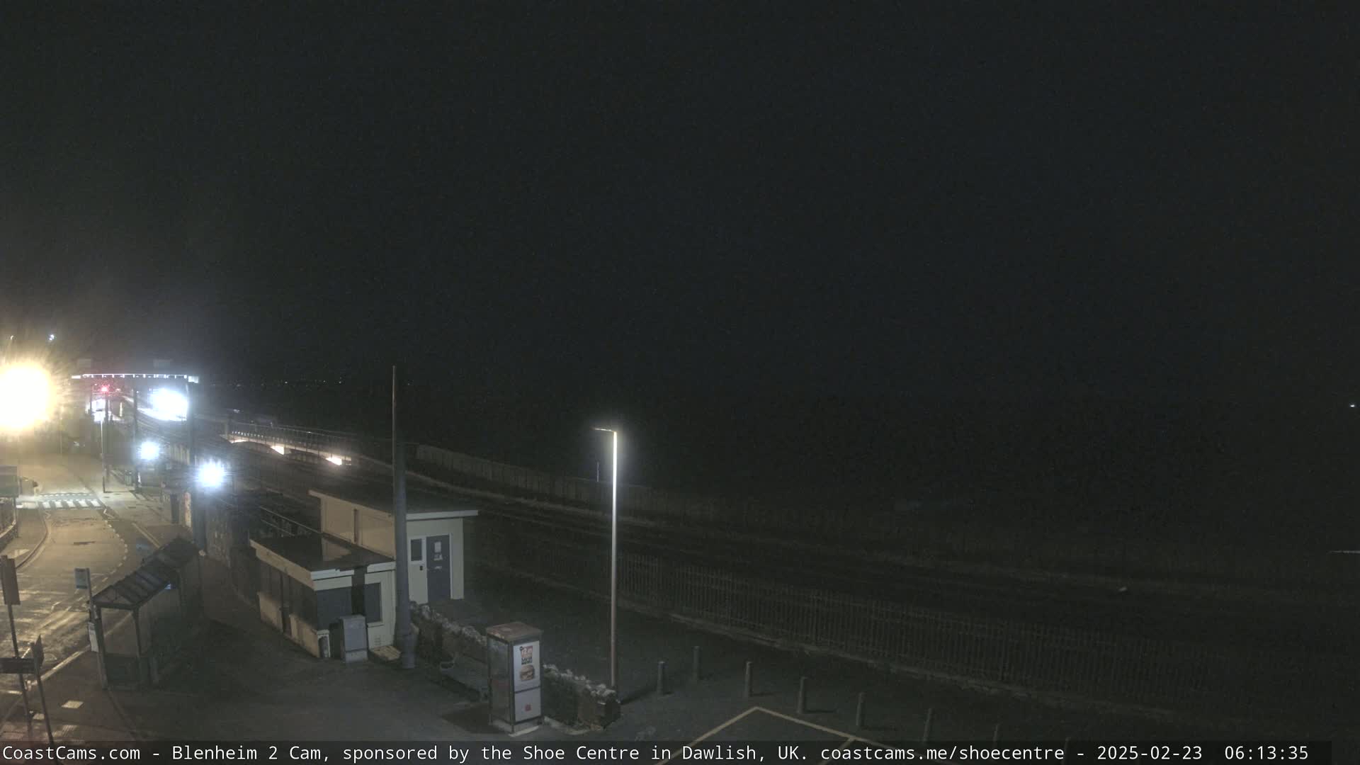 A nighttime view of a mostly empty train platform and surrounding area.