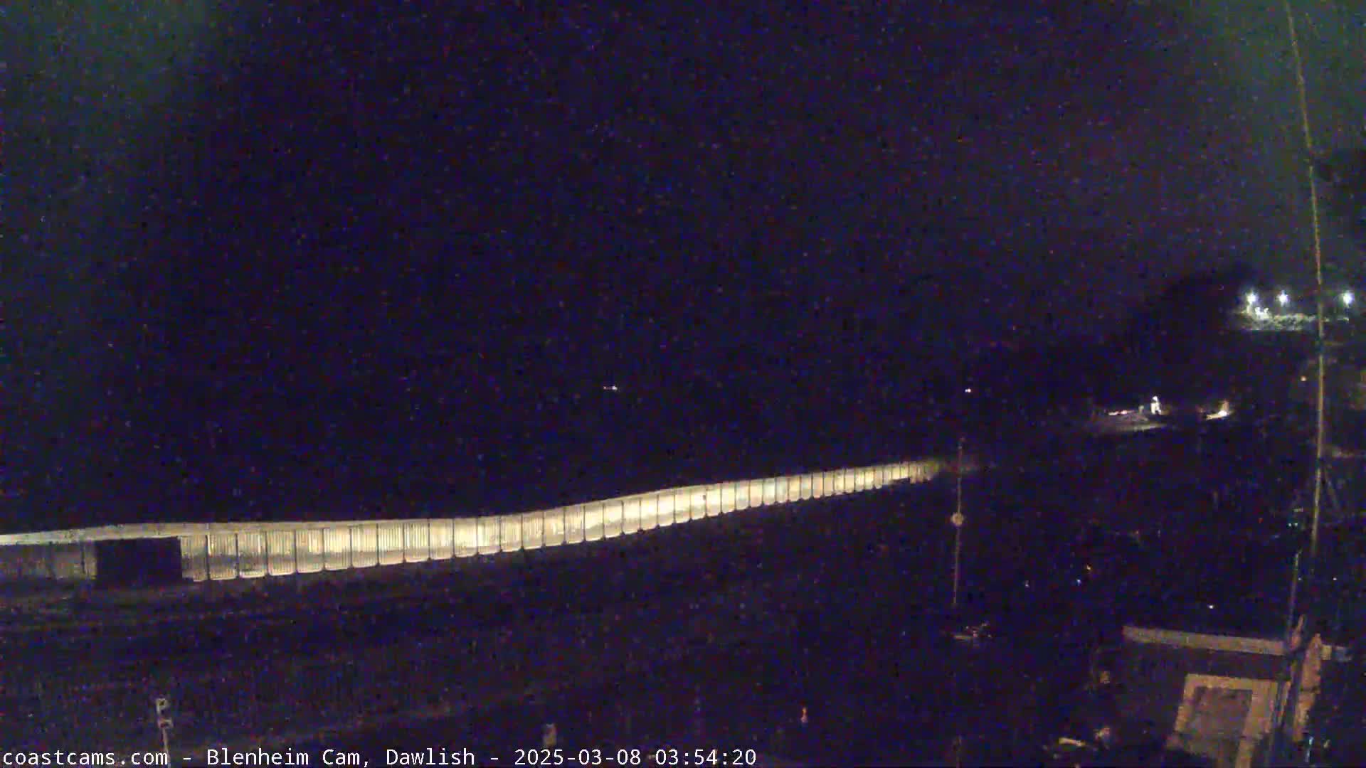 A long, illuminated barrier stretches across a dark, nighttime scene.