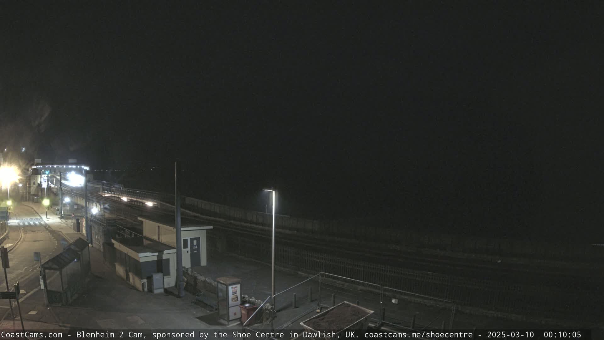 A nighttime view of a train station platform and surrounding area under a dark, clear sky.