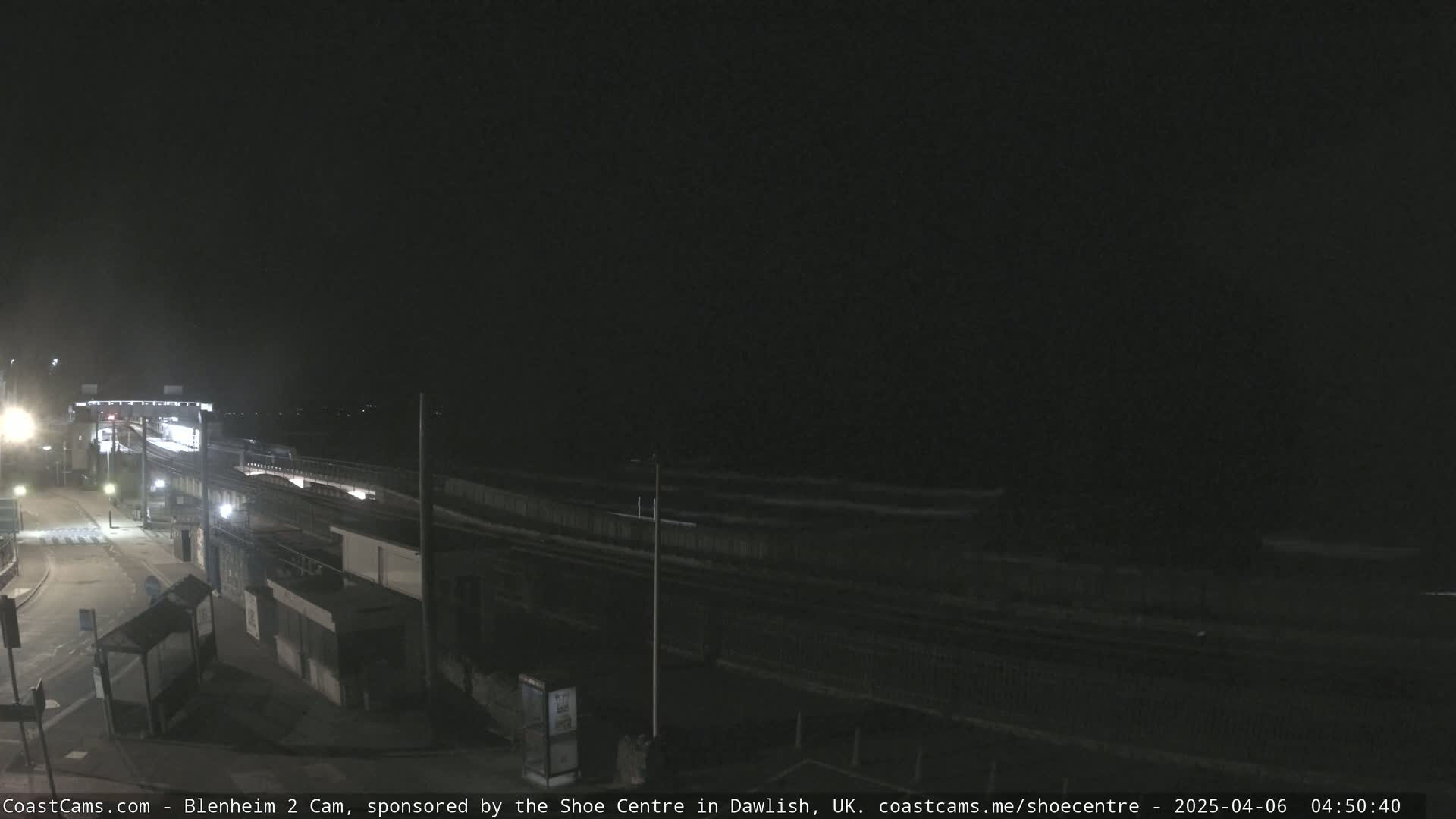 A nighttime view of a train station and nearby roadway under a dark sky.