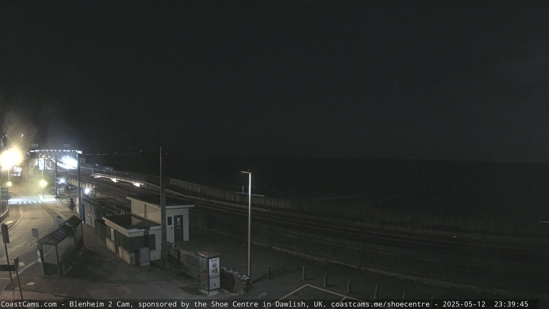 A nighttime view of a train station platform and surrounding area under a dark sky.