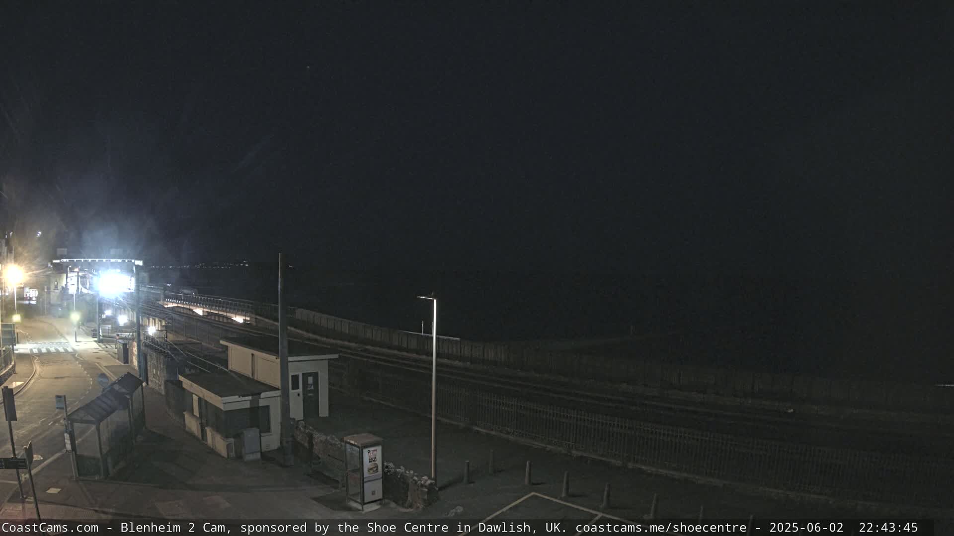 A nighttime view of a train station and coastal area under a clear, dark sky.
