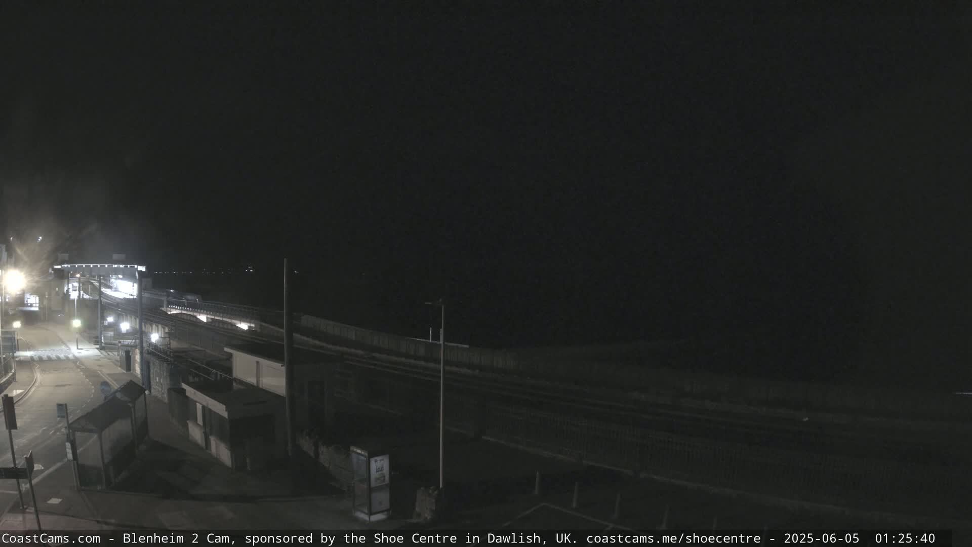 A nighttime view of a mostly empty train station platform and surrounding area.