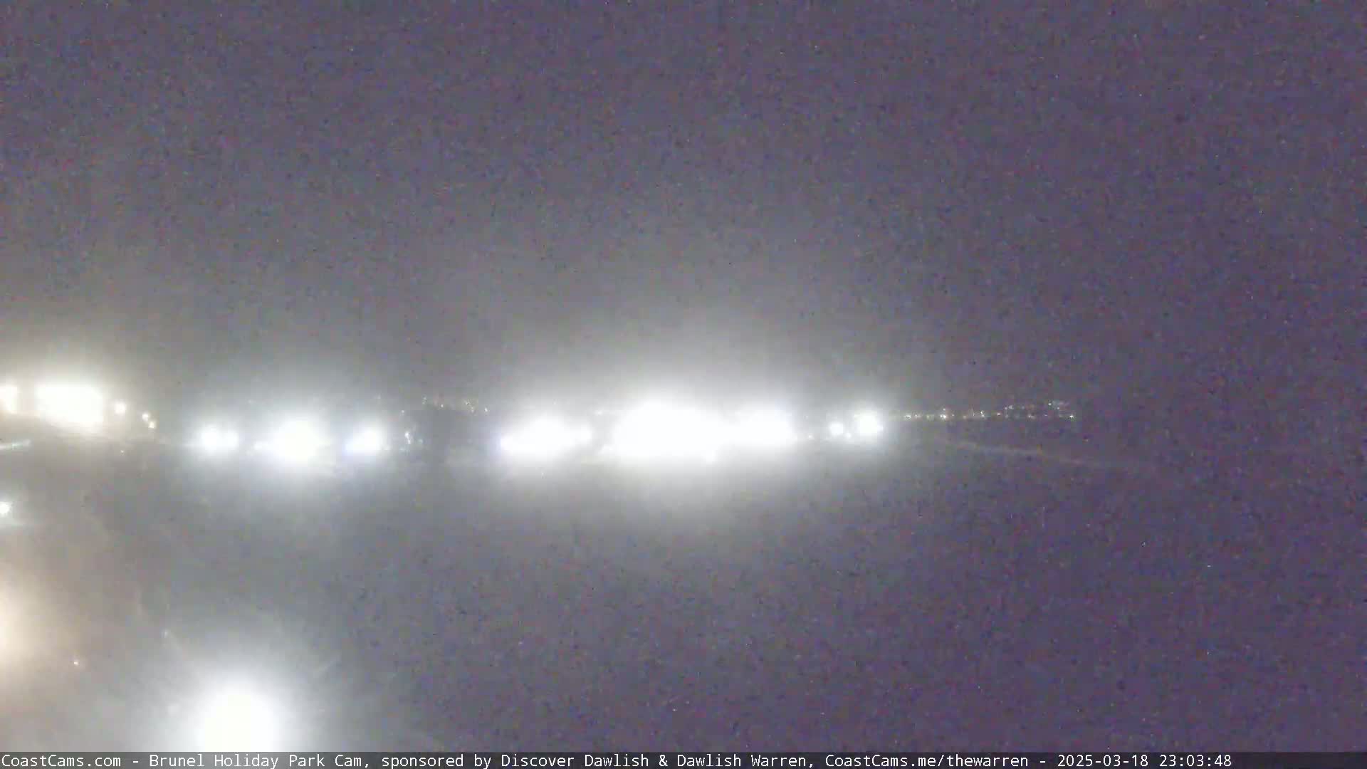 A hazy night scene shows a line of headlights in the distance.
