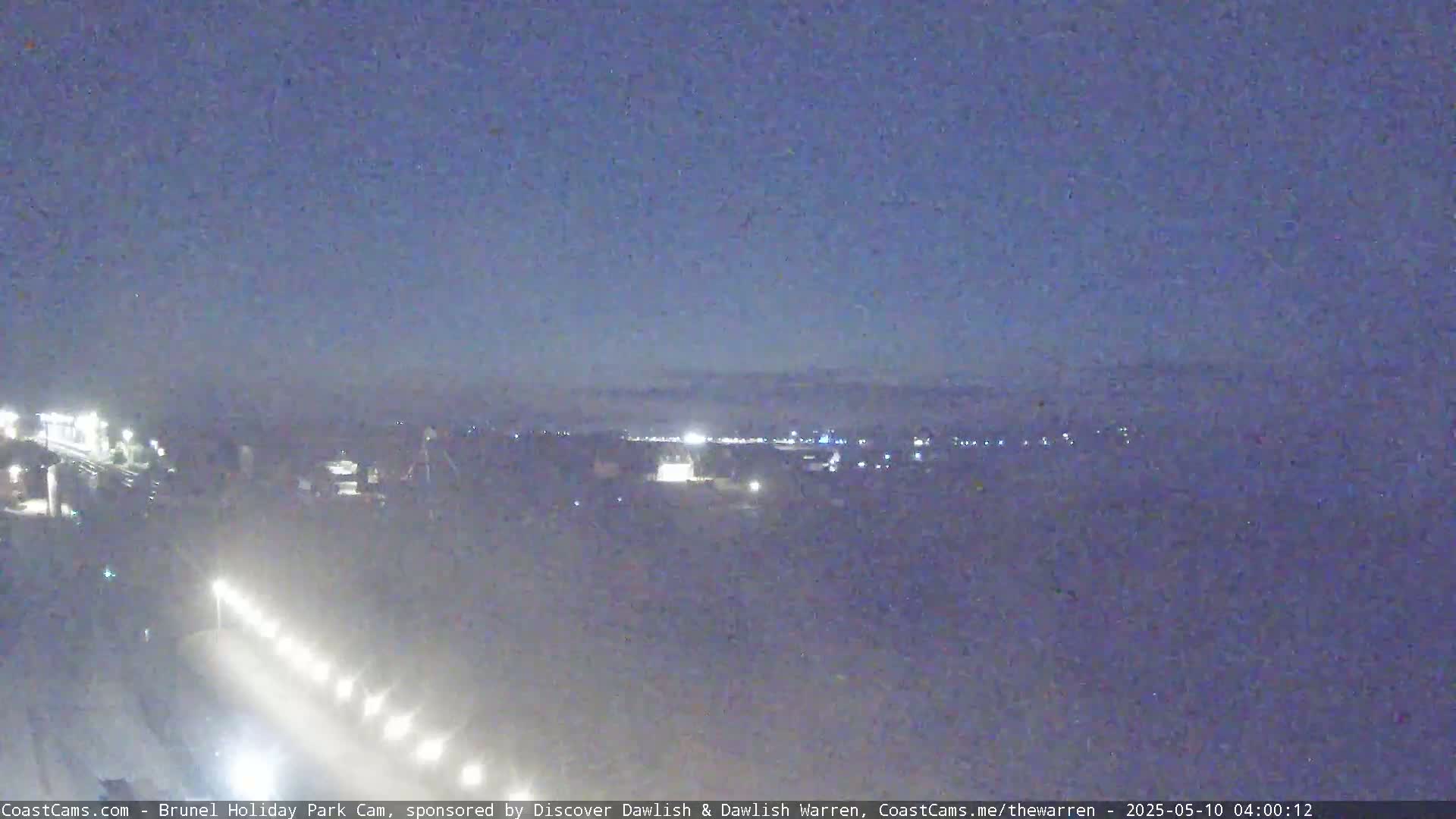 A nighttime long shot shows a highway with lights, buildings in the distance, and a hazy sky.