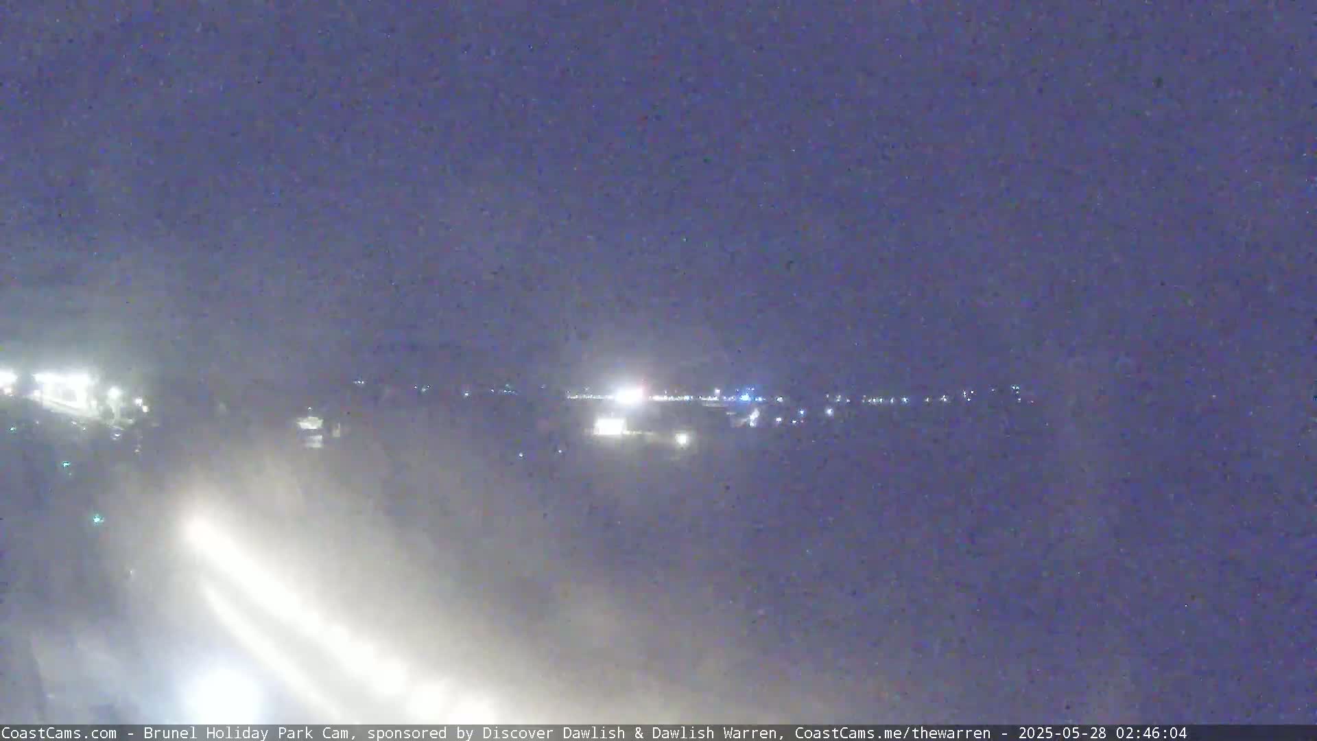 A hazy night scene shows distant lights across a flat landscape.