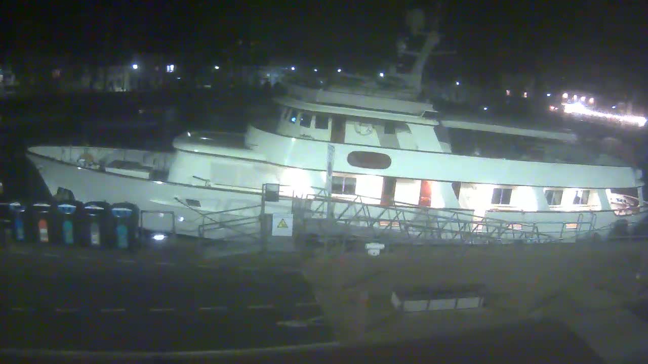 A large, white motor yacht is docked at night.