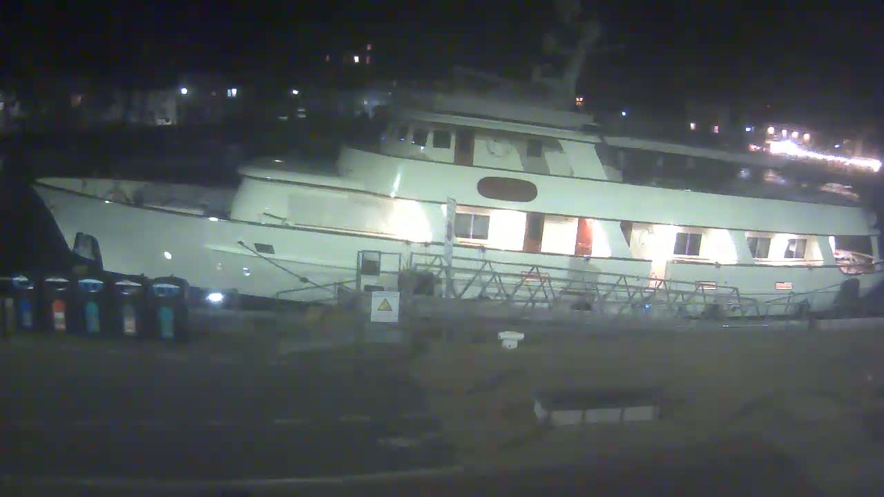 A large, white motor yacht is docked at night.