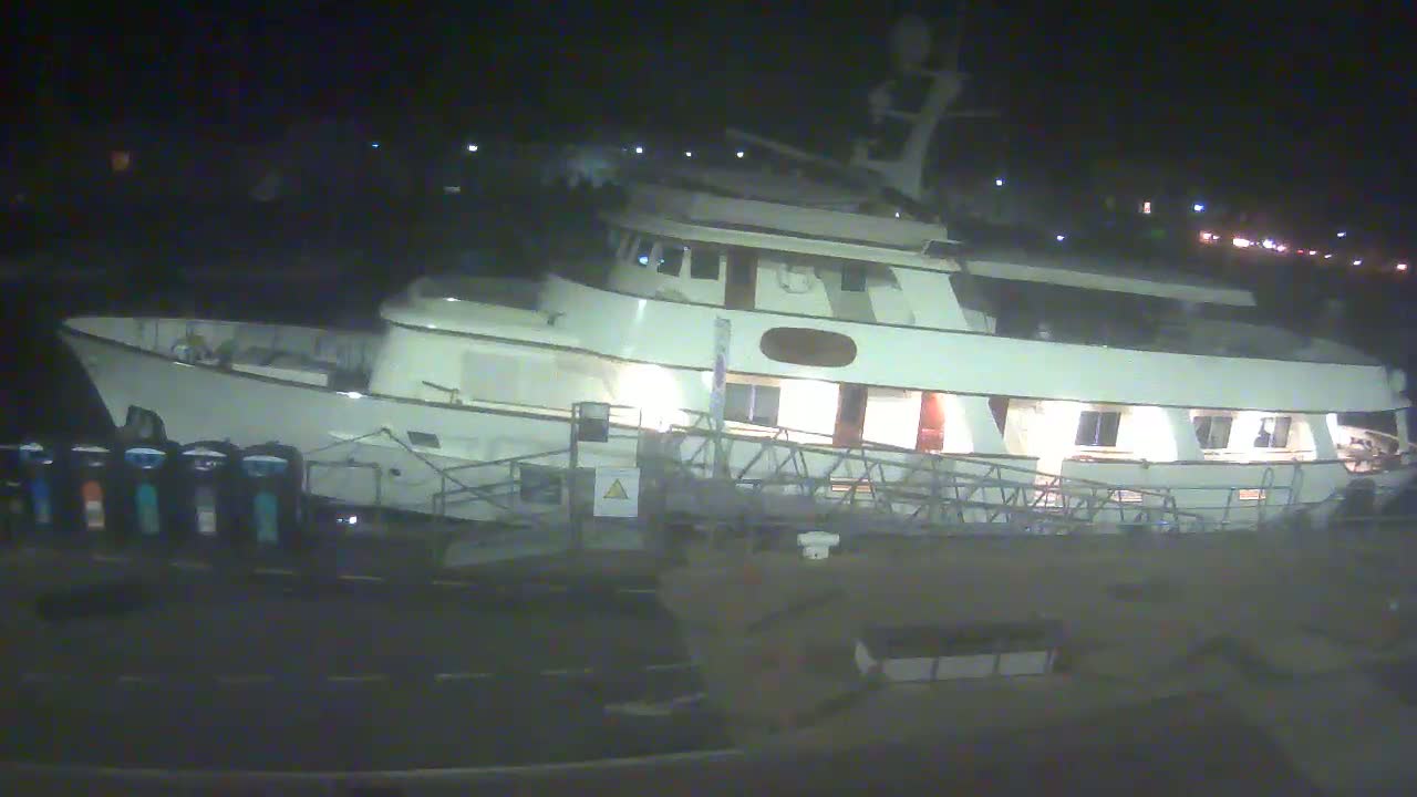 A large, white motor yacht is docked at night.