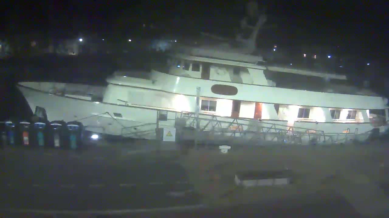 A large, white motor yacht is docked at night.