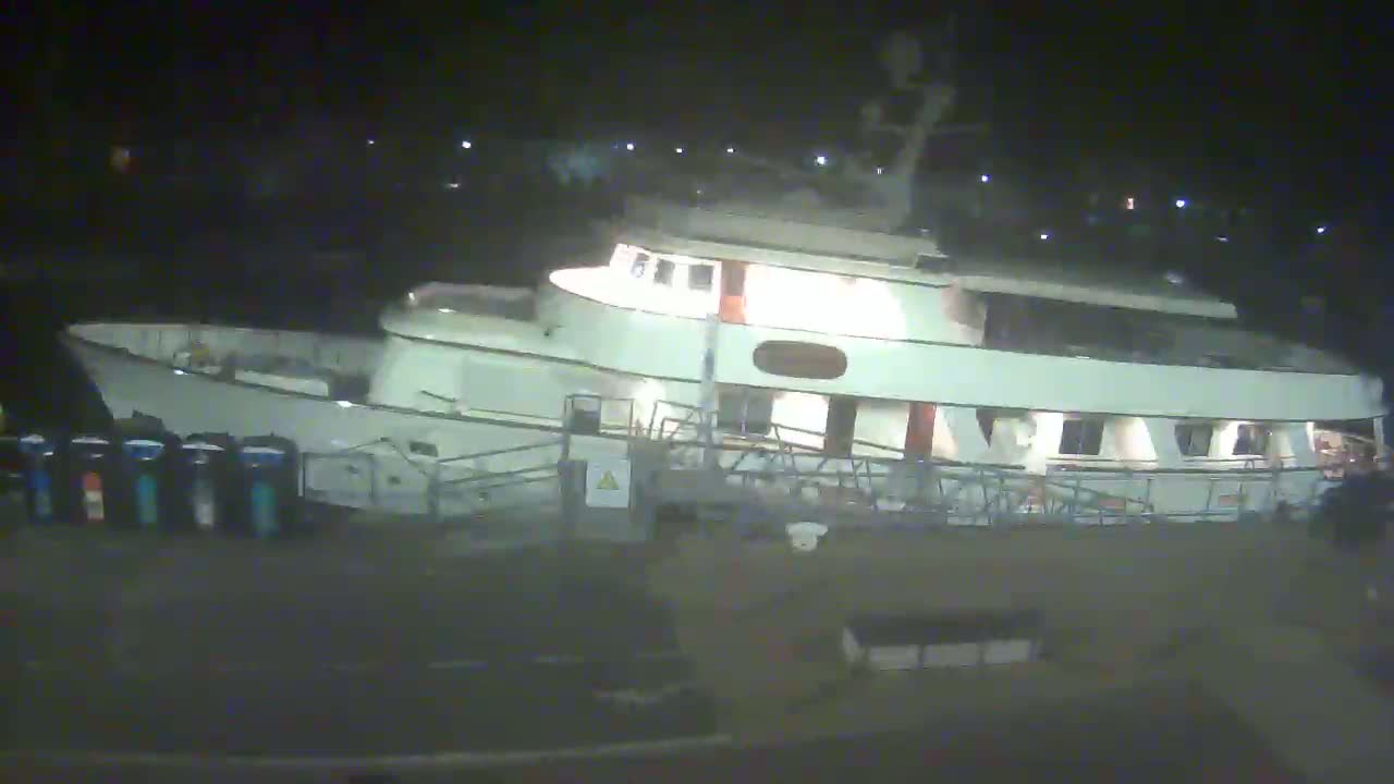 A large, white motor yacht is docked at night.