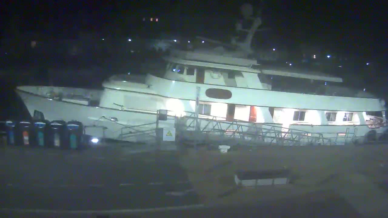 A large, white motor yacht is docked at night.