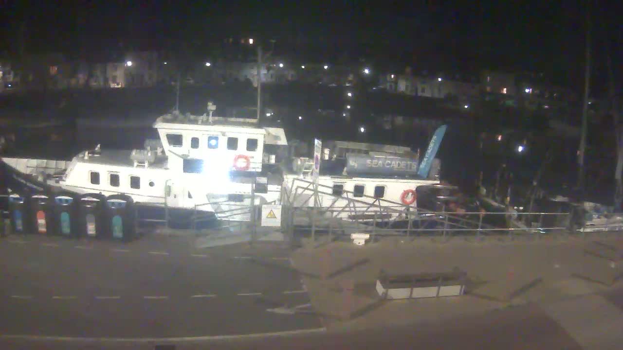 Two boats are docked at a harbor at night.