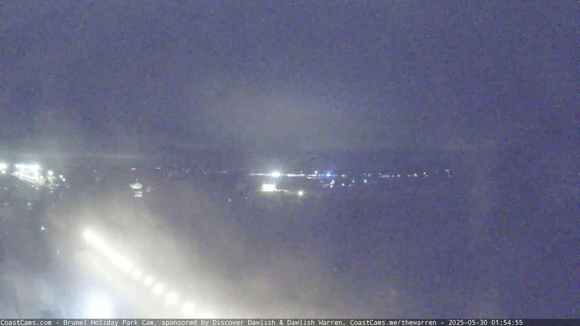 A nighttime, hazy long shot of a dimly lit landscape with distant lights.