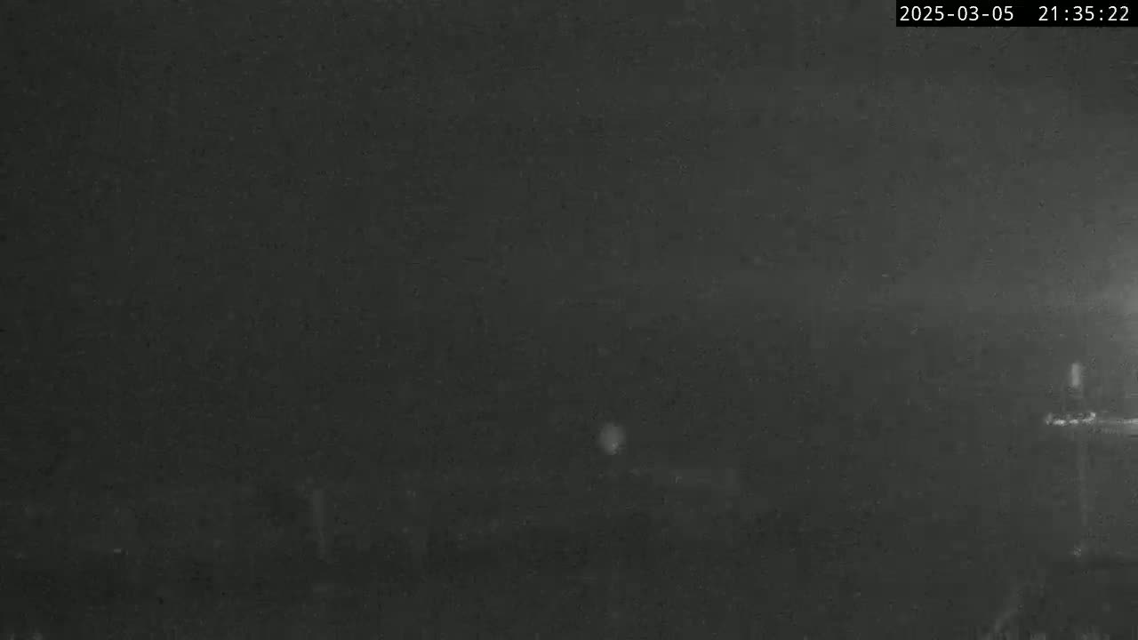 A nighttime, dark, and blurry outdoor scene shows a mostly indistinct landscape under a dark sky.